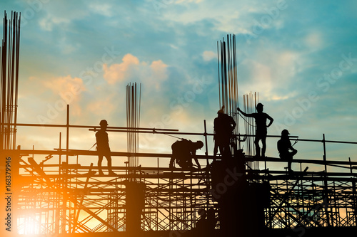 Silhouette construction industry team safely to work load concrete building according to set goal over blurred background sunset pastel for industry background.