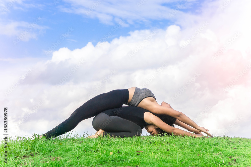 Fototapeta premium Woman twin practicing yoga relax in nature and blue sky background