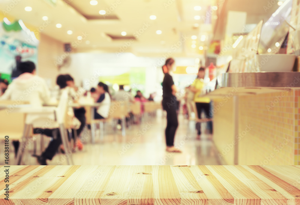 Food court or foodcourt interior blurred background. Restaurant or canteen with table, people at indoor plaza, mall, store or shopping center. Include empty wooden counter or desk for product display. Food court or foodcourt interior blurred background. Restaurant or canteen with table, people at indoor plaza, mall, store or shopping center. Include empty wooden counter or desk for product display.
