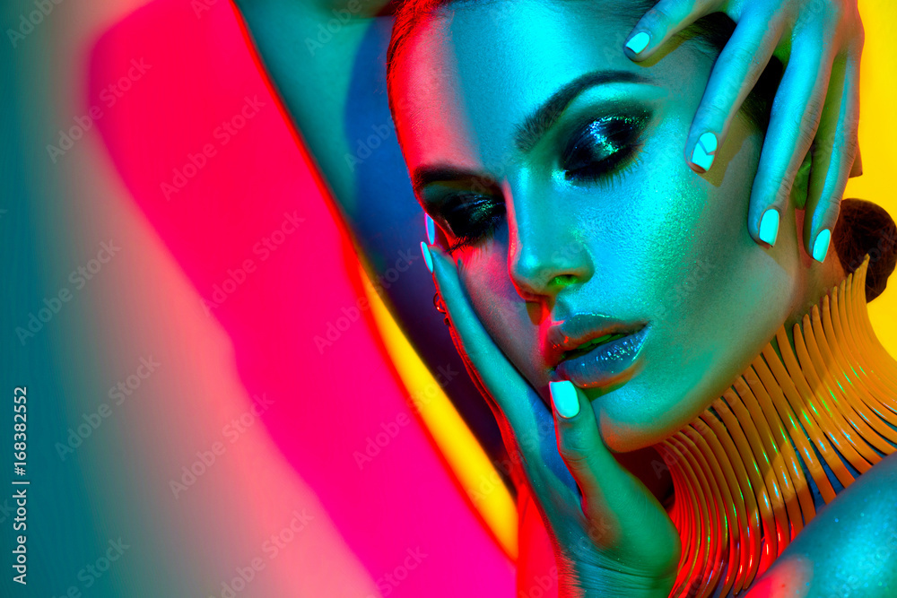Fashion model woman in colorful bright lights with trendy makeup and manicure posing in studio - obrazy, fototapety, plakaty 