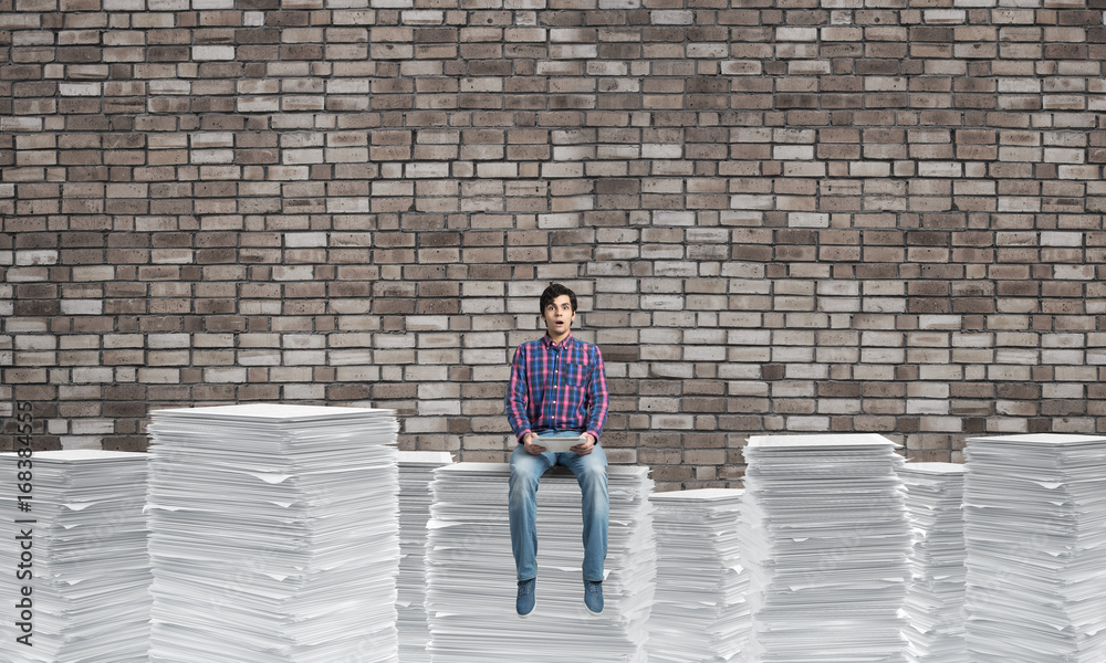 Attractive man sitting on pile of paper documents. Attractive man sitting on pile of paper documents.