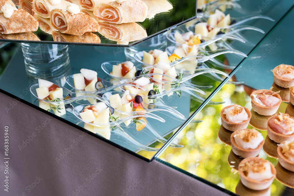 Appetizers, finger food, party food, sliders. Canape, tapas. Served table at summer terrace cafe. Catering service. Outdoor restaurant table with food.