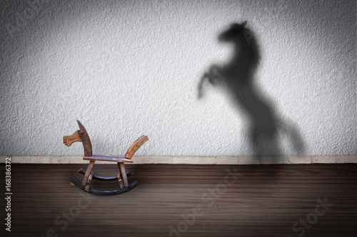The concept of the hidden potencial.Toy horse in the room which casts a shadow on the wall. photo
