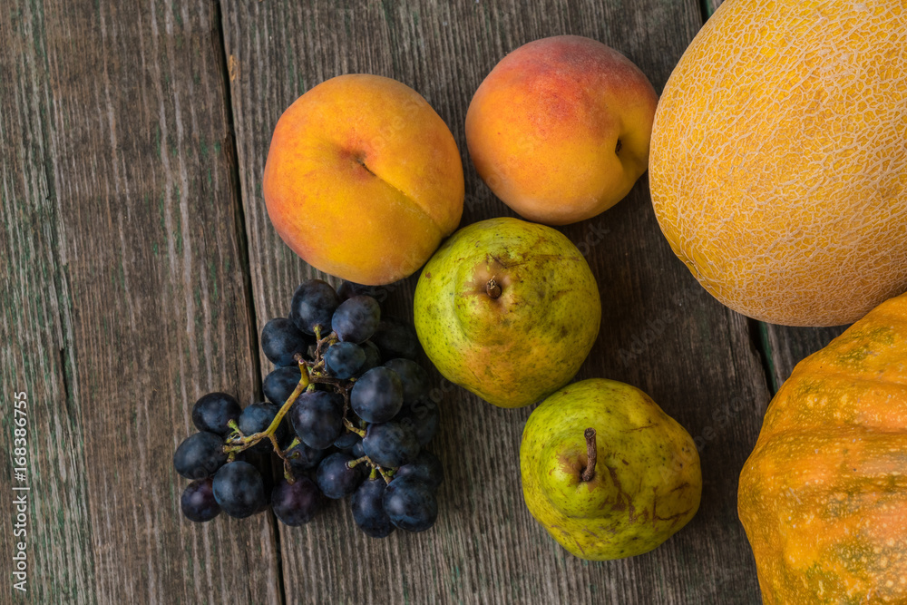 Melon, grapes, peach, Pear and pumpkin on old wooden table.