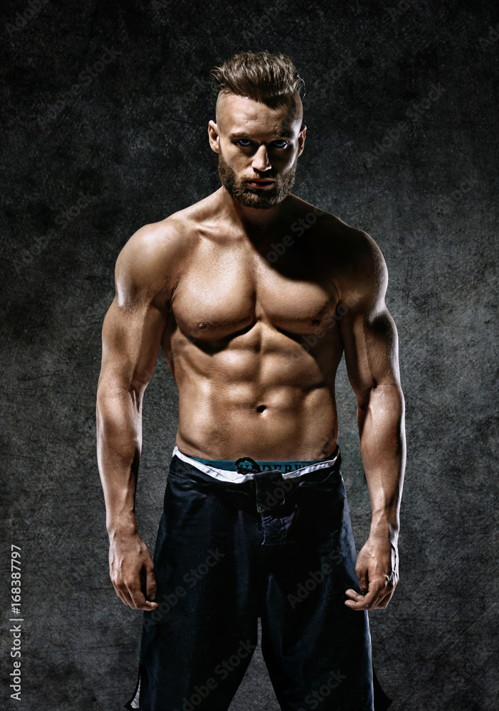 Sporty man with perfect body after training on dark background. Strength and motivation