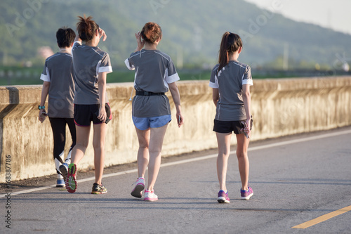 Healthy sports people trail running living an active life. Happy lifestyle athletes training cardio together in summer outdoors. Group woman runs on the sports track back view.