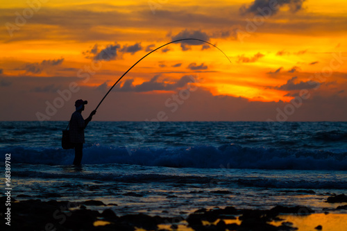 Fisherman silhouette on sunset tropical beach, Phuket, Thailand.