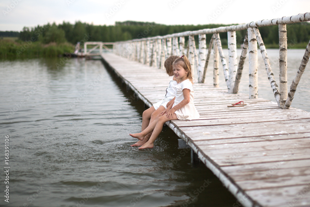sisters Kicks feet on lake, childhood, light tone sisters Kicks feet on lake, childhood, light tone