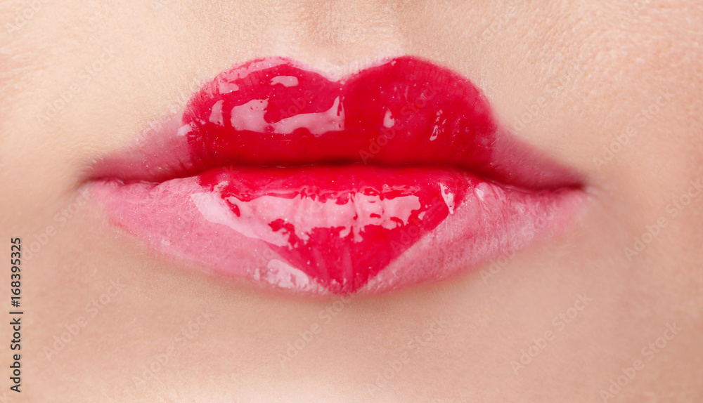 Obraz premium Heart painted with gloss on female lips, closeup