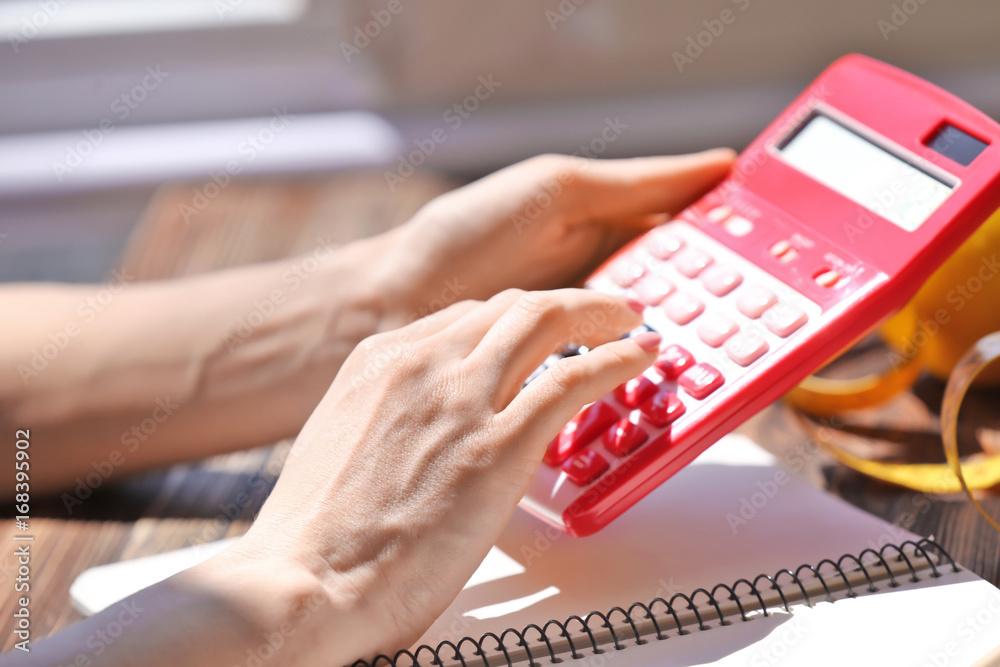 Obraz premium Young woman calculating calories at table. Weight loss concept