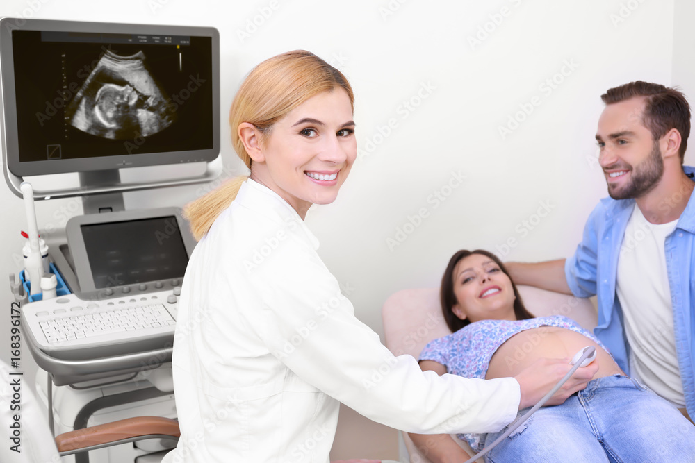 Young pregnant couple undergoing ultrasound scan in clinic Young pregnant couple undergoing ultrasound scan in clinic