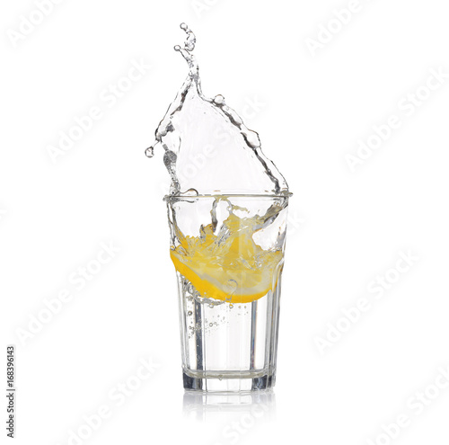 Fresh slice of lemon falling into glass with water on white background