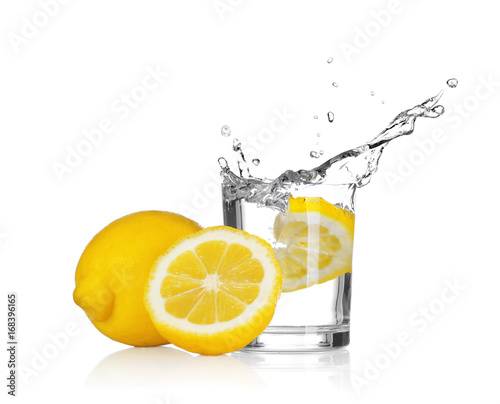 Fresh slice of lemon falling into glass with water on white background