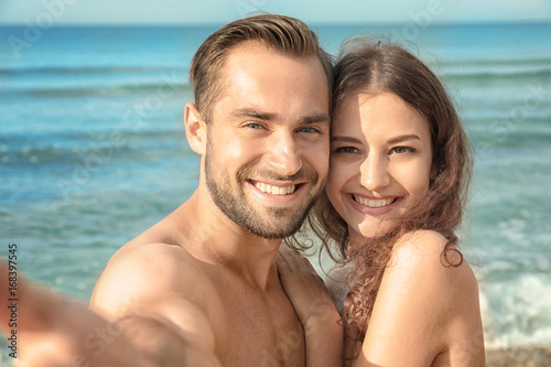 Beautiful young couple taking selfie at sea resort