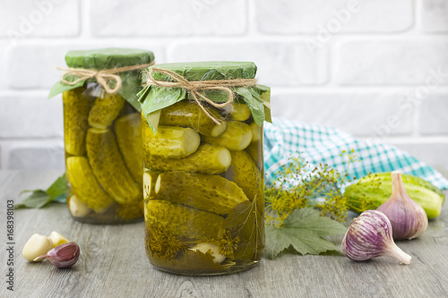 Pickled cucumbers in glass jar on a gray wooden table.