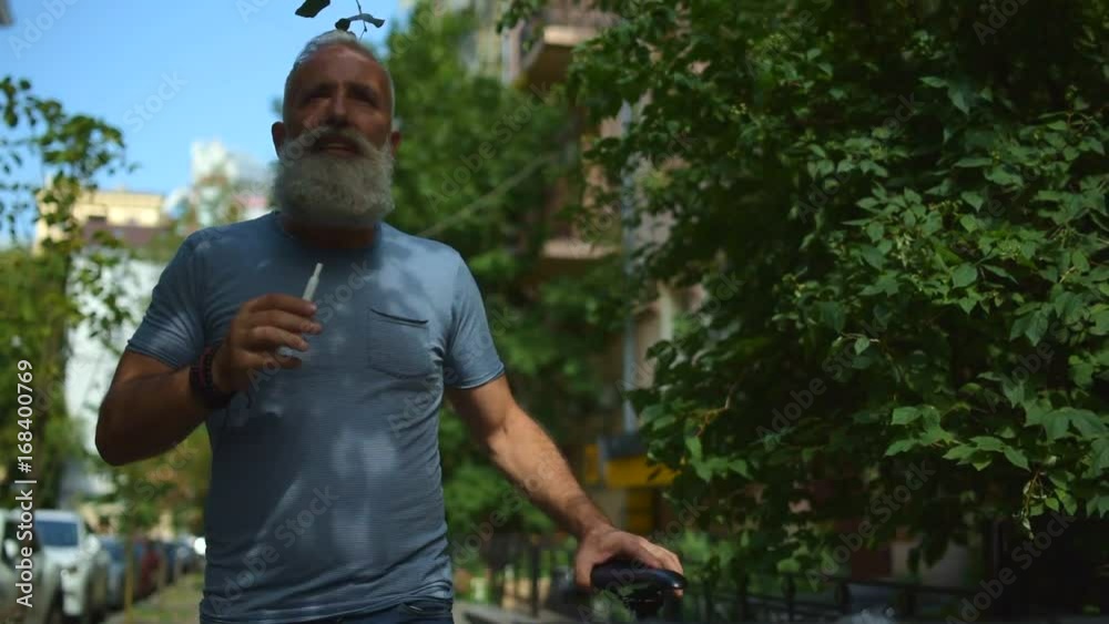 Joyful man smoking while promenading with bicycle Joyful man smoking while promenading with bicycle