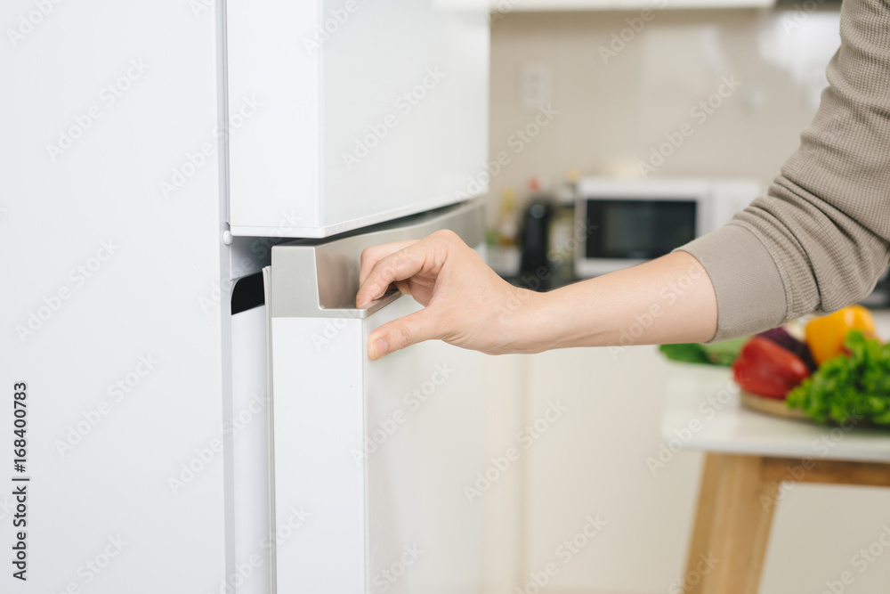Male hand is opening white refrigerator door