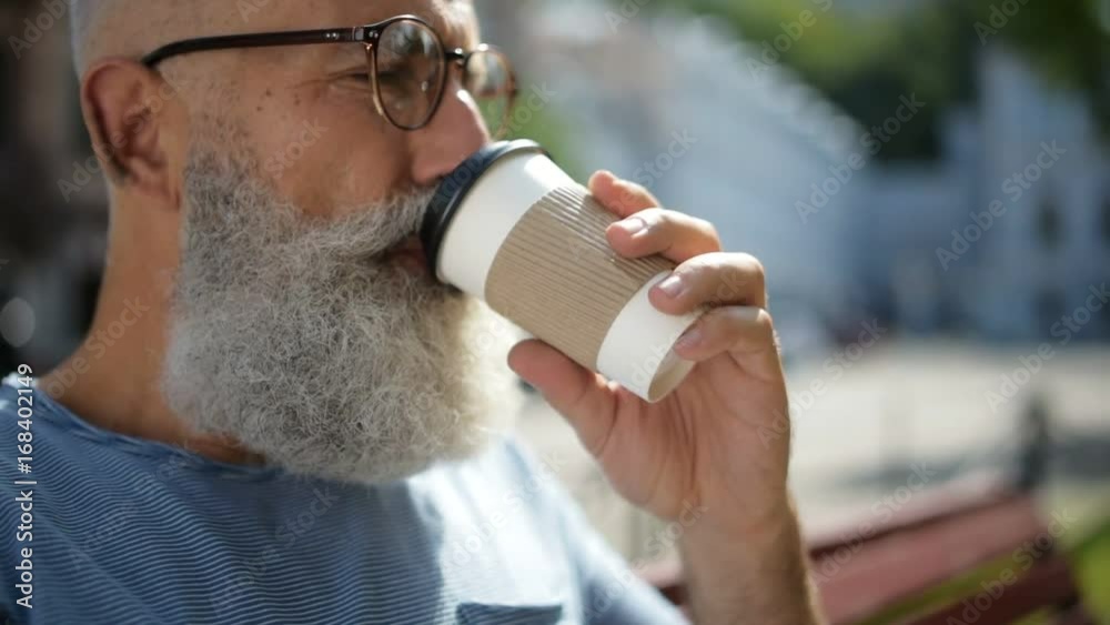Senior gentleman wearing glasses drinking coffee outdoors