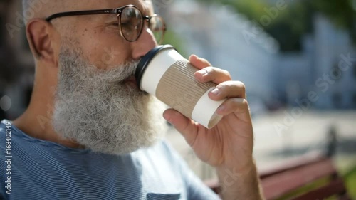 Senior gentleman wearing glasses drinking coffee outdoors
