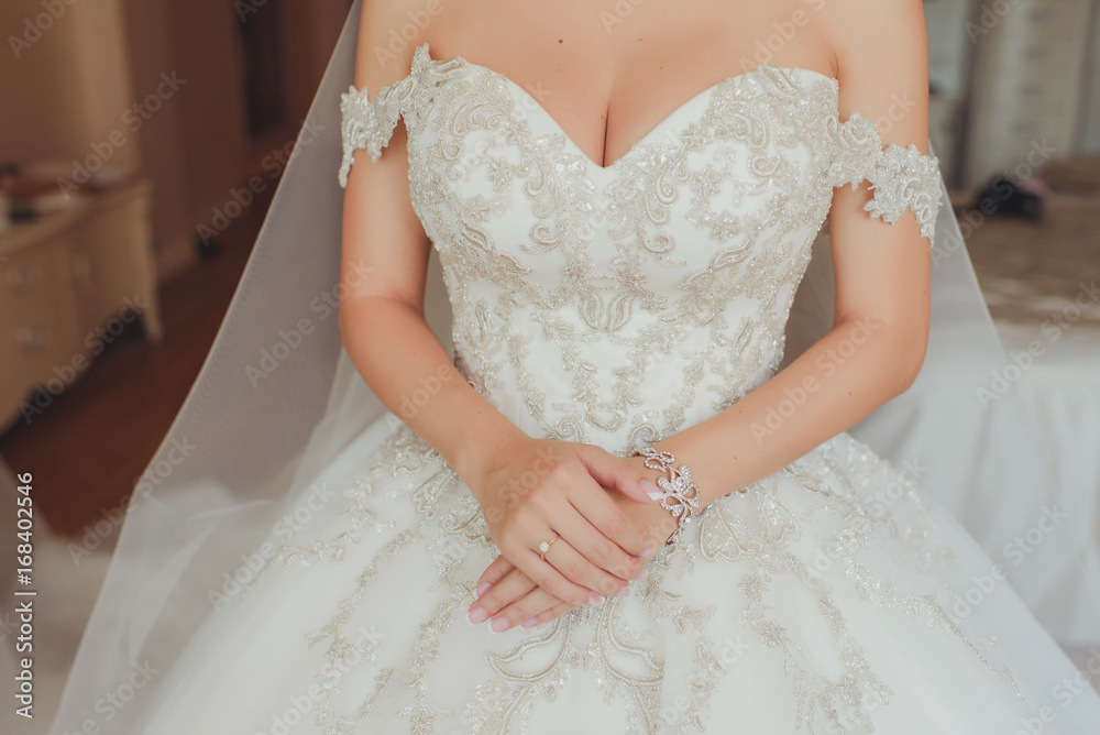 Руки невесты на дорогом пышном свадебном платье с вышивкой