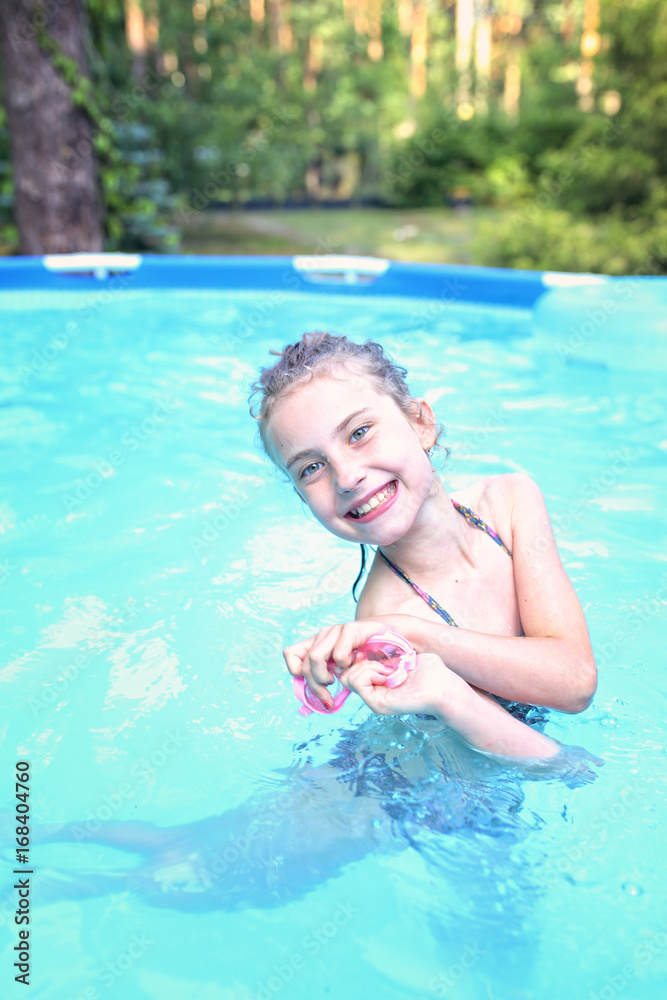 Young girl in the pool in a warm summer day