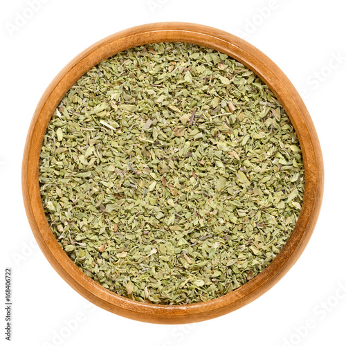 Oregano dried in wooden bowl. Origanum vulgare, sometimes wild marjoram. Herb with aromatic olive green leaves and a slightly bitter taste. Isolated macro food photo close up from above over white.