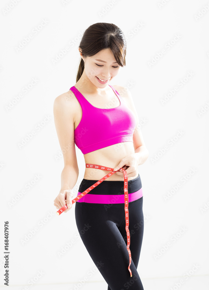Fit young woman taking measurements of her body Fit young woman taking measurements of her body