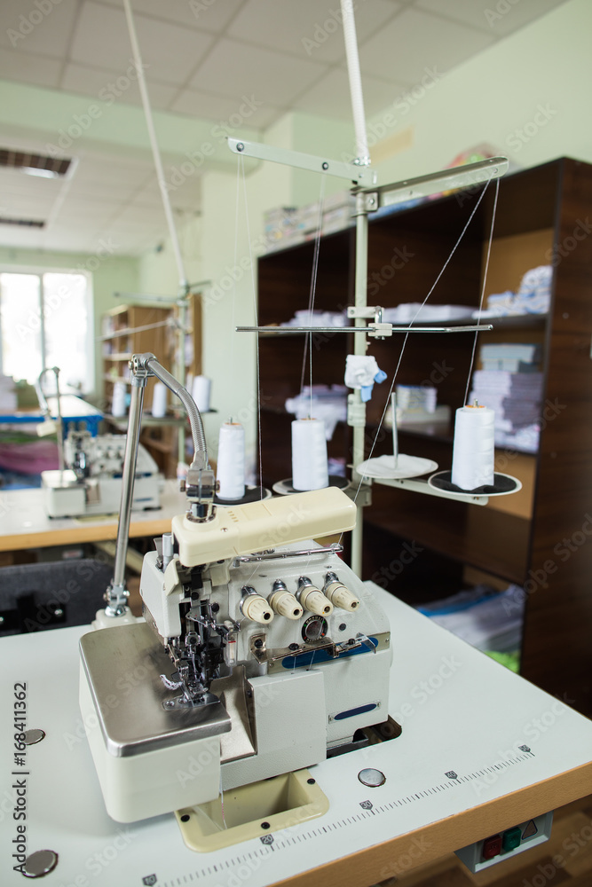 Closeup of professional sewing machine in factory interior.  Vertical color image.
