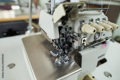 Closeup of details of professional sewing machine in factory interior. Horizontal color image.