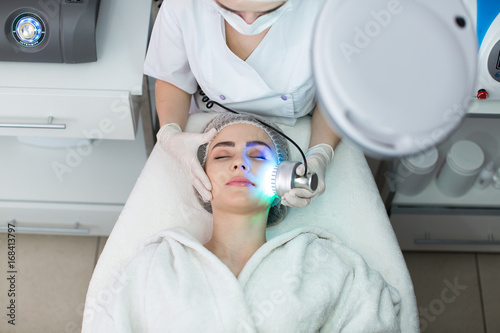 Ultrasonic massager. Light skin treatment, the woman in the beauty salon photo