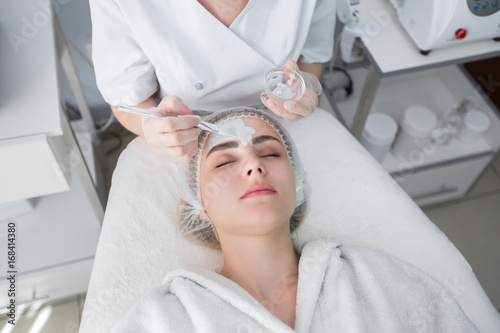 Face peeling mask, spa beauty treatment, skincare. Woman getting facial care by beautician at spa salon