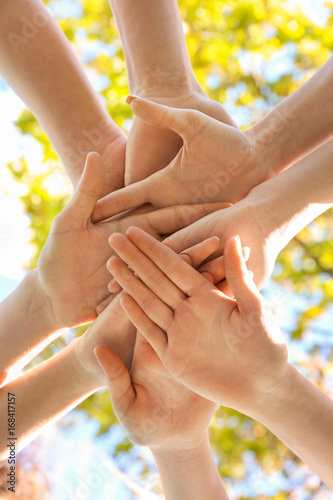 Young people putting hands together outdoors. Volunteer concept