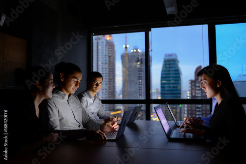 business man and business woman working with computer overtime at night and low light in the office