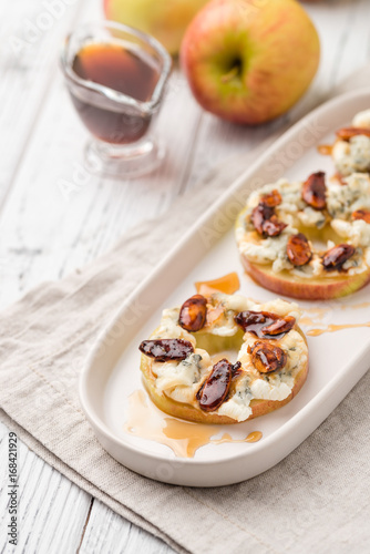 Apple circles with cream cheese, gorgonzola and spicy almond nuts with honey. Rustic white wooden table