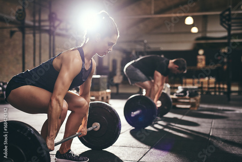 Sportive people holding barbells before doing deadlift photo