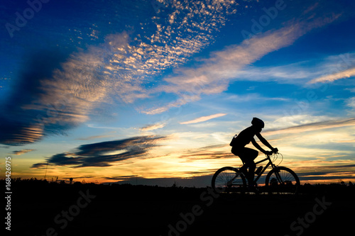 Silhouette of cyclist in motion on the background of beautiful sunset,ride bicycle on sunset background,Silhouette of man ride a bike in sunset background. photo