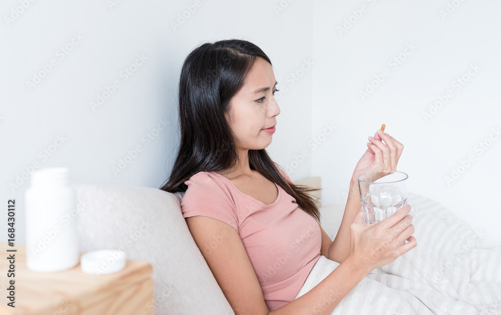 Young Woman taking pills and holding glass of water Young Woman taking pills and holding glass of water