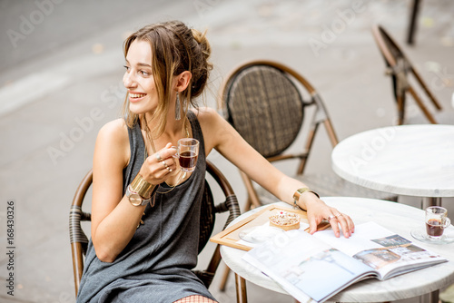 Photography Young stylish woman in gray dress drinking coffee outdoors at the cafe in Paris