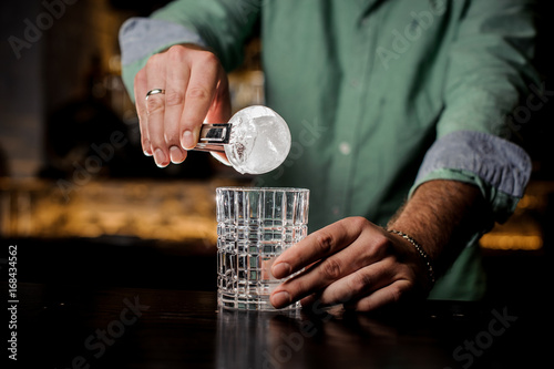 A professional bartender is holding an ice ball. photo