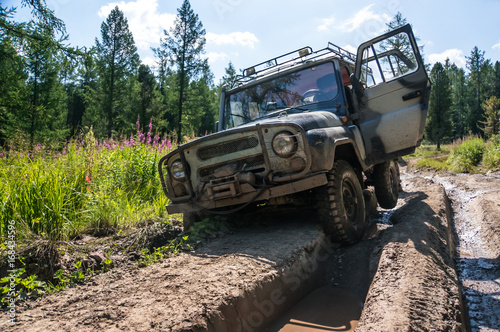 Wall Mural SUV stuck in a rut on a bad impassable road in the woods of Siberia