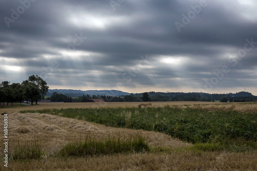 Sun rays going through dark clouds on the picturesque landscape of Moravia early in the morning