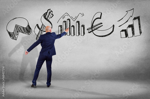 Businessman in front of a wall writing on hand drawn business interface - business concept photo