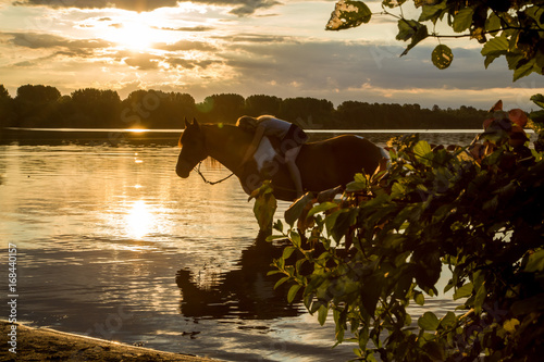 Reiterin im Sonnenaufgang im See