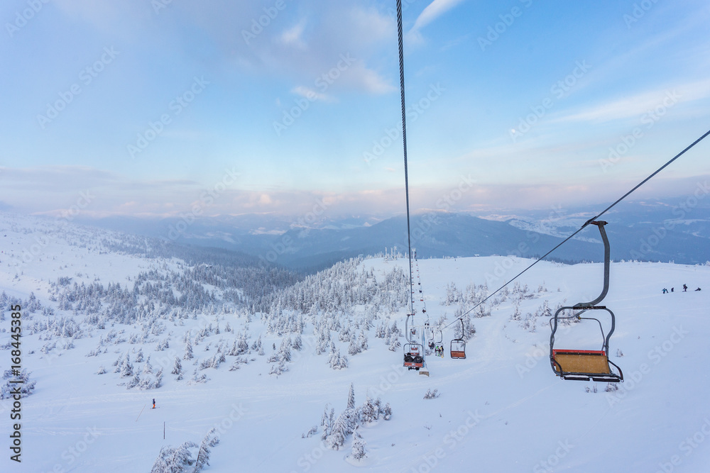 Ski lift with seats going over the mountain and paths from skies Ski lift with seats going over the mountain and paths from skies