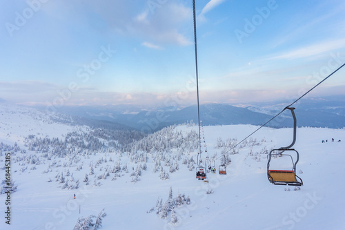 Ski lift with seats going over the mountain and paths from skies photo