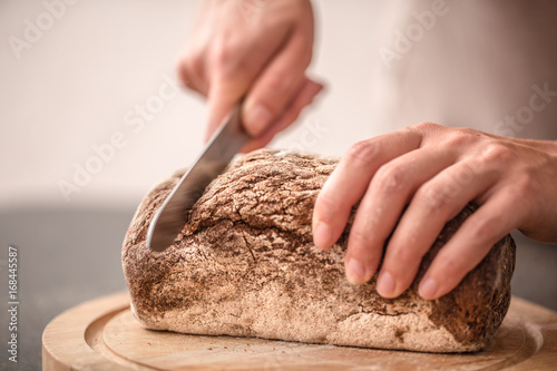 fresh bread in hands closeup on old wooden background