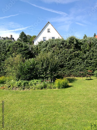 Großer Garten mit grünem Rasen, Busch und Strauch im Sommert vor blauem Himmel im Sonnenschein in Wettenberg Krofdorf-Gleiberg bei Gießen in Hessen photo