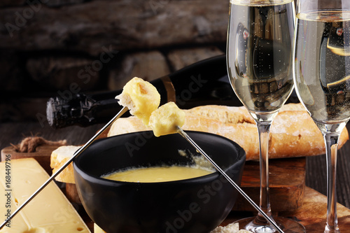 Foto Gourmet Swiss fondue dinner on a winter evening with assorted cheeses on a board