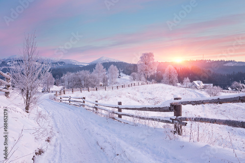 Winter country landscape with timber fence and snowy road