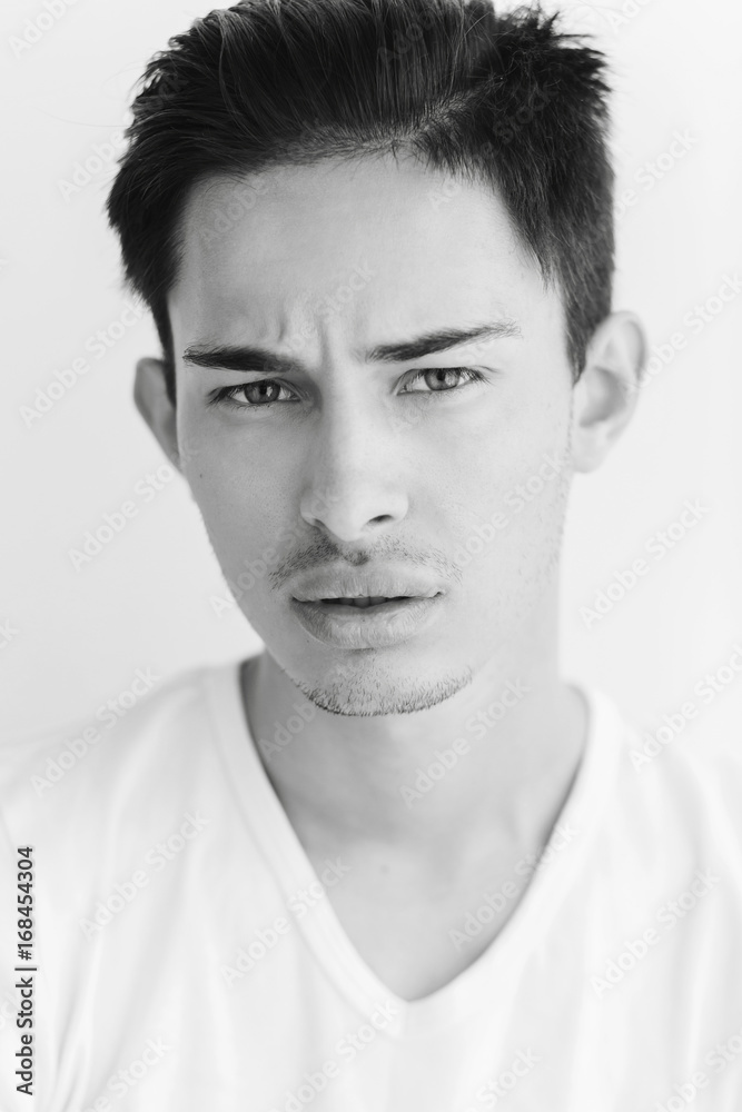 Portrait of a young man with dark hair and light eyes. on a white background. The guy in the white T-shirt. Male model. Black and white portrait of a young man Portrait of a young man with dark hair and light eyes. on a white background. The guy in the white T-shirt. Male model. Black and white portrait of a young man